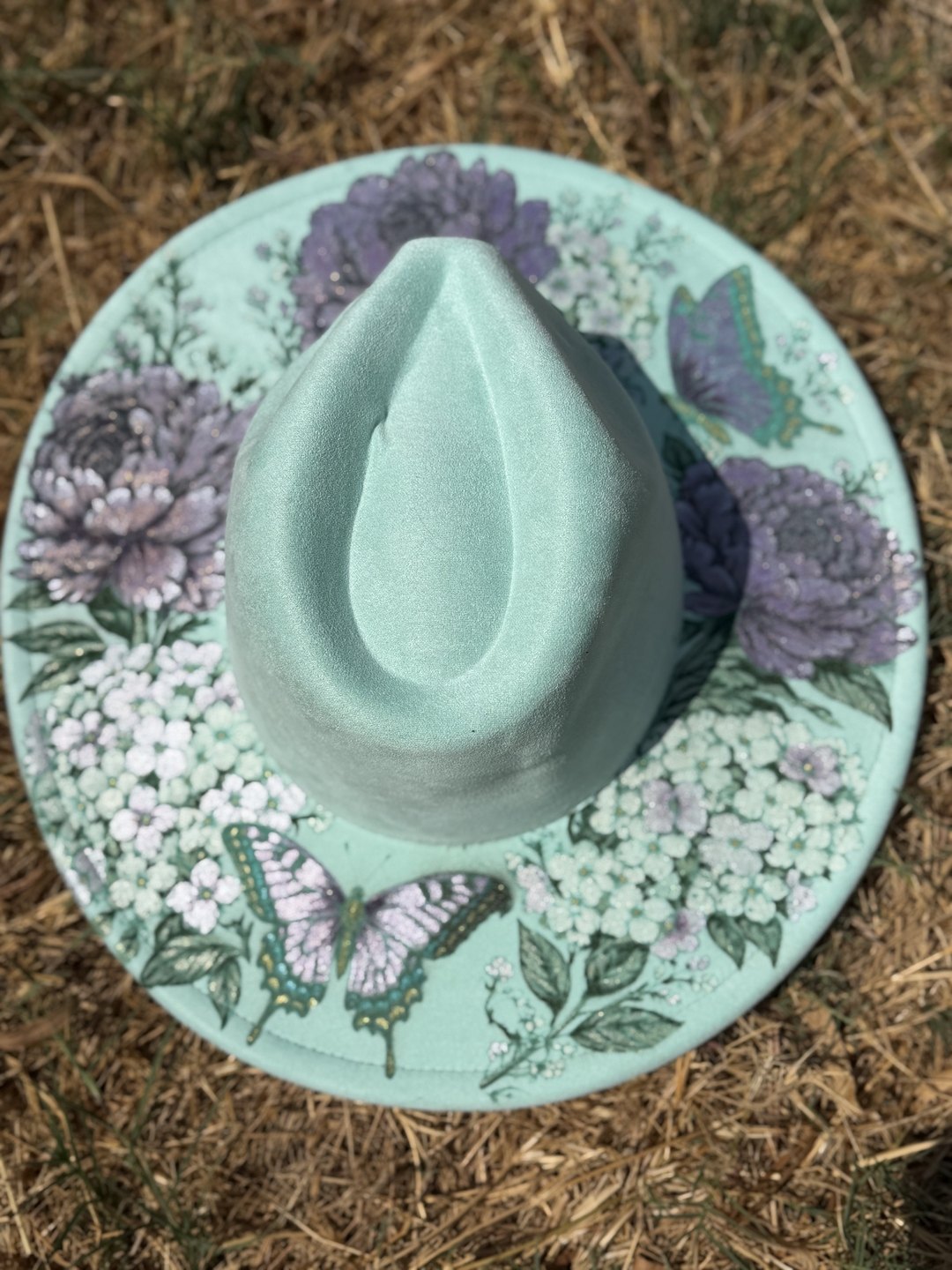 Mint green hat shown top-down with full circular brim of purple peonies and butterflies